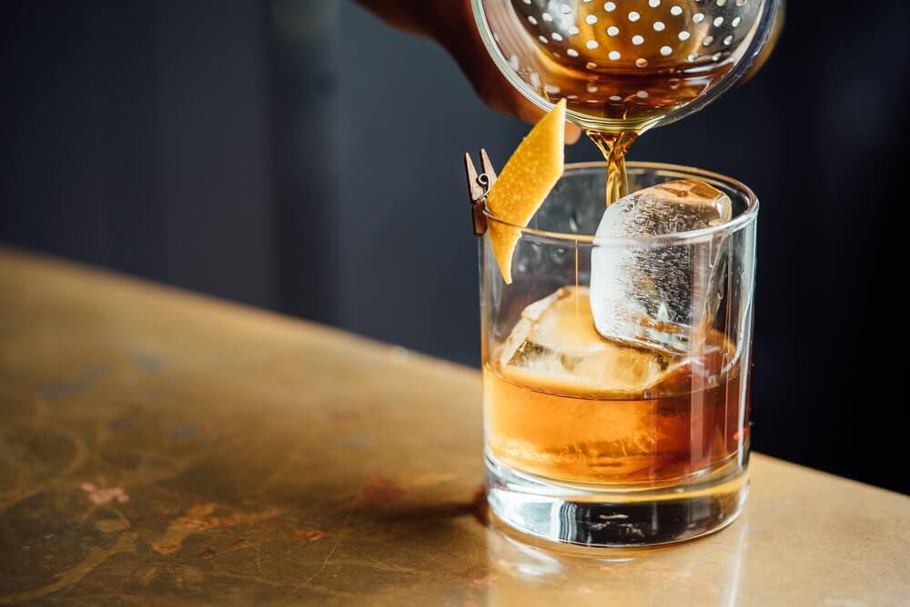 A cocktail being poured into a glass